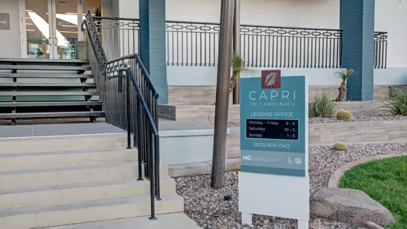 Close-up of the Capri on Camelback leasing office sign with business hours and contact information.