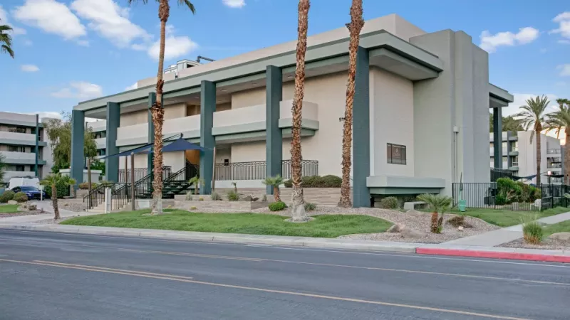 Street view of the Capri on Camelback building surrounded by palm trees and a clean, modern facade.