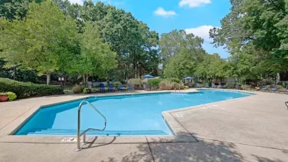 A large pool with crystal-clear water, surrounded by nature and ample seating.
