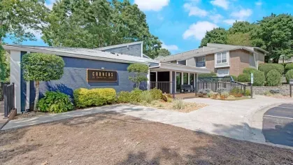 The leasing office at Corners at Crystal Lake, featuring a welcoming blue facade and vibrant landscaping.