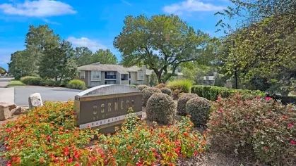 A beautifully landscaped entrance sign for Corners at Crystal Lake, surrounded by colorful flowers and greenery.
