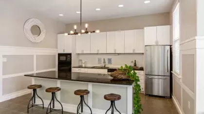 A contemporary kitchen with white cabinetry, a black granite island, and stylish bar stools.