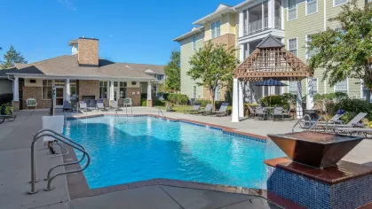 A sparkling outdoor swimming pool surrounded by lounge chairs and shaded seating areas.