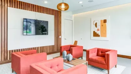 A cozy media lounge with vibrant red armchairs, a large wall-mounted TV, and modern wooden paneling for a stylish yet inviting space.