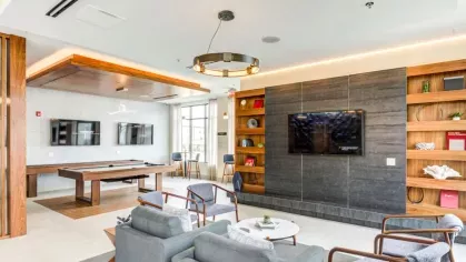 A contemporary entertainment lounge featuring a pool table, multiple TV screens, and cozy seating, offering the perfect environment for relaxation and social gatherings.