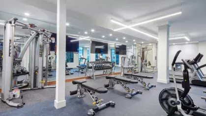 A spacious fitness center at The Everly Luxury Apartments, featuring state-of-the-art weightlifting machines, cardio equipment, and mirrored walls for an enhanced workout experience.