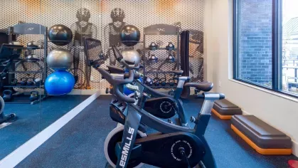 A modern cycling studio with Les Mills stationary bikes, mirrored walls, and floor-to-ceiling windows, offering an immersive spin workout experience.