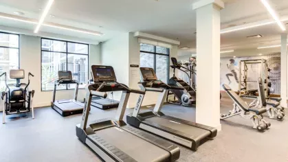 The cardio zone at The Everly Luxury Apartments, equipped with treadmills, ellipticals, and weight benches, illuminated by large windows that bring in natural light.