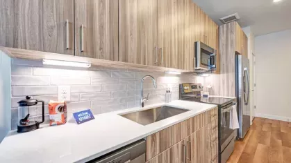 A beautifully lit kitchen with stylish cabinetry, under-cabinet lighting, and a tiled backsplash, offering a perfect blend of function and aesthetics.