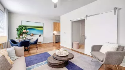 An airy living space with a dining area, an open kitchen, and a sliding barn door leading to the bedroom, designed for comfort and functionality.