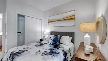 A serene bedroom with a floral-patterned bedspread, soft lighting, and a sophisticated wooden nightstand at The Everly Luxury Apartments.