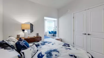 A modern bedroom with a walk-in closet, leading into a stylish dining space filled with natural light.