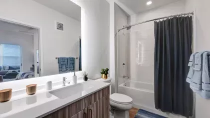 A contemporary bathroom with a large mirror, sleek vanity, and a tiled shower with a deep blue curtain for a spa-like feel.