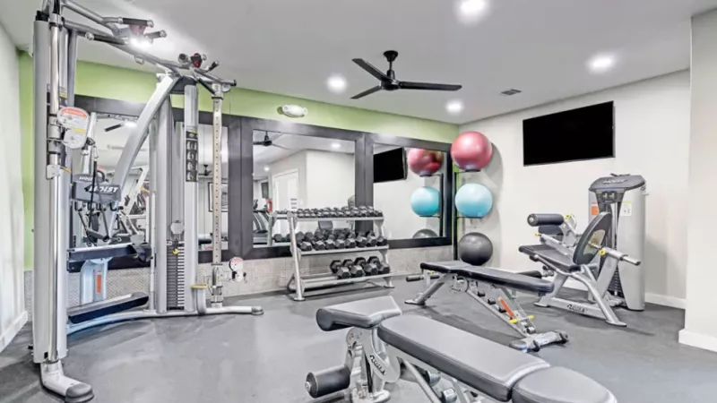 Modern fitness center with weight training equipment, resistance machines, and exercise balls.