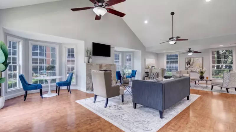 Well-lit lounge area with high ceilings, ceiling fans, and a mix of modern and traditional seating.