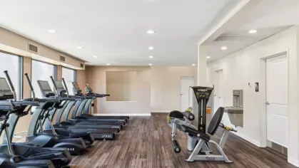 Well-equipped gym with a row of treadmills and a variety of strength training equipment.