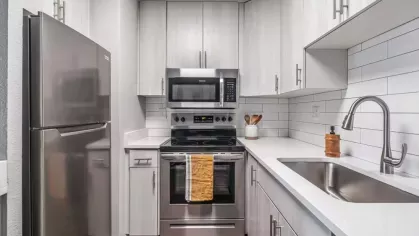 Contemporary kitchen with stainless steel appliances, white cabinets, and subway tile backsplash.