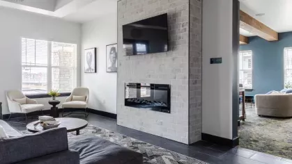 A sleek living area with a modern fireplace, a mounted TV, and comfortable seating arranged around a round coffee table.