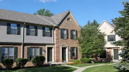 Classic townhouse-style apartments with brick facades, green shutters, and welcoming front doors.