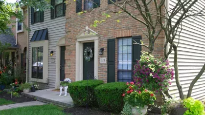 Cozy townhouse entrance with a decorative wreath and colorful potted flowers.
