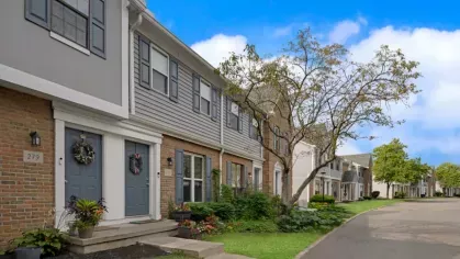 A row of charming townhouses with gray and brick exteriors along a quiet residential street.
