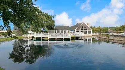 A serene lakefront clubhouse with large windows and a deck overlooking the water.