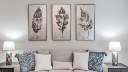 Comfortable living area with a neutral-toned sofa, modern decor, and a ceiling fan, ideal for relaxation.