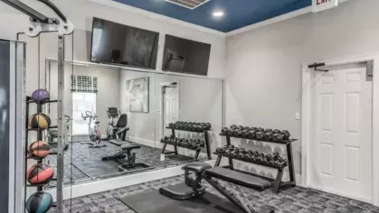 Fitness studio with free weights, strength equipment, and mirrored walls at The Landings of Conroe Luxury Apartments.