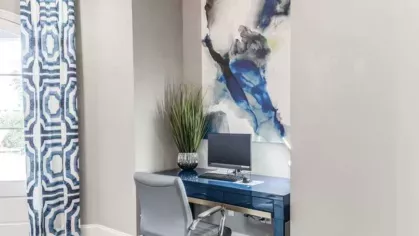Cozy workspace nook at The Landings of Conroe with a sleek blue desk, comfortable office chair, and modern abstract artwork, ideal for remote work or studying.