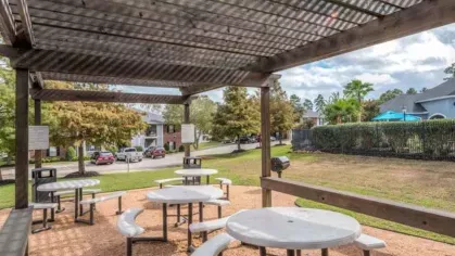 Shaded picnic pavilion with modern white tables and benches at The Landings of Conroe, offering a perfect spot for outdoor dining and gatherings.