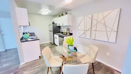 Cozy dining area featuring a round glass table with cream-colored chairs, complemented by contemporary decor and bright lighting.