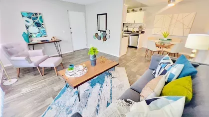 Open-concept living and dining space with modern furnishings, wood-style flooring, and large windows for natural light, offering a comfortable and stylish living environment.