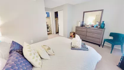 Another view of the bedroom showcasing a dark wood dresser, a mirror, and complementary decor, creating a peaceful and organized retreat.