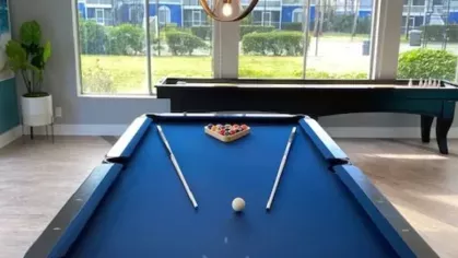 Recreation room with a blue pool table, large windows, and a shuffleboard table.