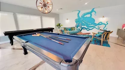 Game room featuring a blue pool table, vibrant octopus wall art, and cozy seating.
