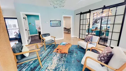 Modern seating area featuring comfortable chairs, a decorative rug, and sliding glass doors leading to additional spaces, blending functionality with aesthetic appeal.