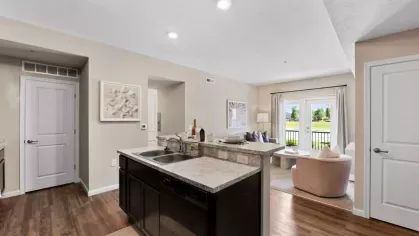 Stylish kitchen with a large island, stainless steel sink, and open living space with natural light at Lawndale Commons Palm Luxury Apartments.