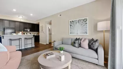 Cozy living room with plush seating, a sleek coffee table, and large windows offering a scenic outdoor view at Lawndale Commons Palm Luxury Apartments.