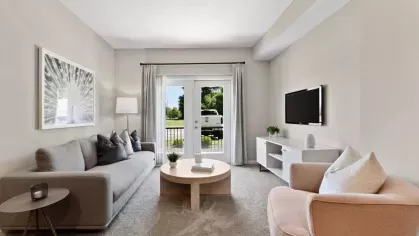 Modern living room with a gray sofa, a chic round coffee table, and floor-to-ceiling windows, creating a comfortable and airy ambiance.