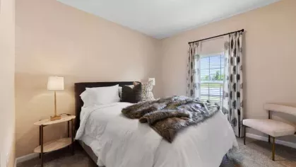 Luxurious bedroom with a cozy faux fur throw, designer decor, and an expansive window offering natural light.
