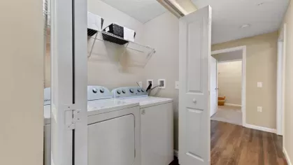 Modern laundry room with a full-size washer and dryer, built-in shelving, and ample storage space.