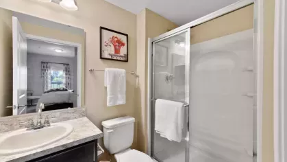 Elegant bathroom featuring a glass-enclosed shower, sleek vanity with a marble countertop, and modern lighting fixtures.