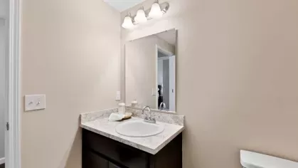 A sleek bathroom featuring a dark wood vanity, marble countertop, and contemporary lighting.