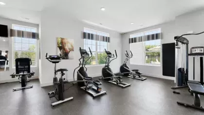 A well-equipped fitness room with elliptical machines, stationary bikes, and strength training equipment.