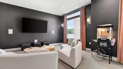 A private movie theater room at Lawndale Commons, complete with plush seating, a large flat-screen TV, and a vintage-style popcorn machine.