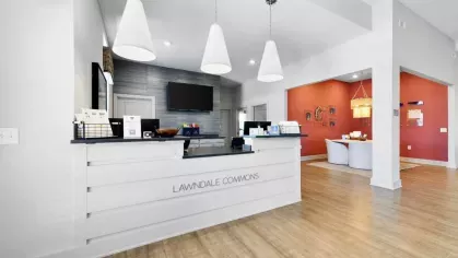 The welcoming leasing office at Lawndale Commons Palm Luxury Apartments, featuring a sleek reception desk, pendant lighting, and a stylish modern interior.