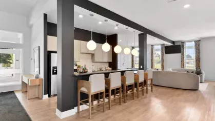 A spacious clubhouse kitchen with a sleek black and white design, high-top seating, and pendant lighting at Lawndale Commons Palm Luxury Apartments.