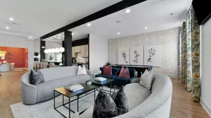 A luxurious clubhouse lounge with plush curved sofas, a pool table, and elegant decor, offering a comfortable social space for residents.