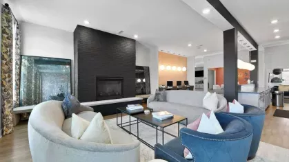 A cozy gathering space at Lawndale Commons featuring a black brick fireplace, modern seating, and a chic open-concept design with a lounge and bar area.