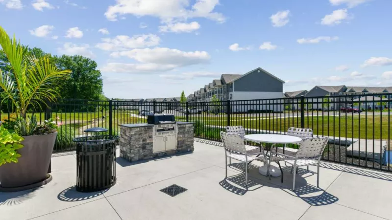A well-appointed outdoor grilling area with a modern barbecue station, seating, and vibrant landscaping.